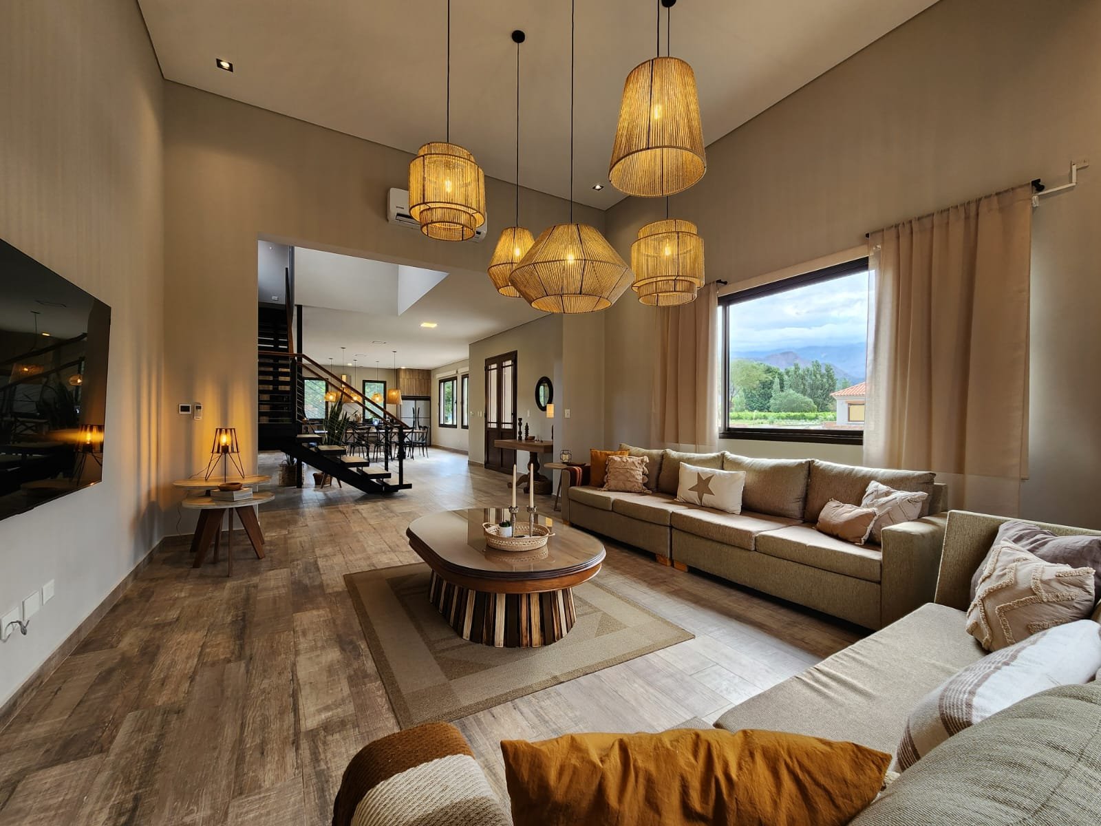 Sala de estar moderna com luminárias pendentes e parede de ripas de madeira — projeto Ca La Estancia, por Luciana González Anderson, em Cafayate